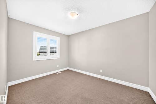 Neutral wall paint, carpet flooring, window with white trim, ceiling-mounted light fixture, and crown molding - 4212 Charles Close Sw, Edmonton, AB - Indoor Photo Showing Other Room