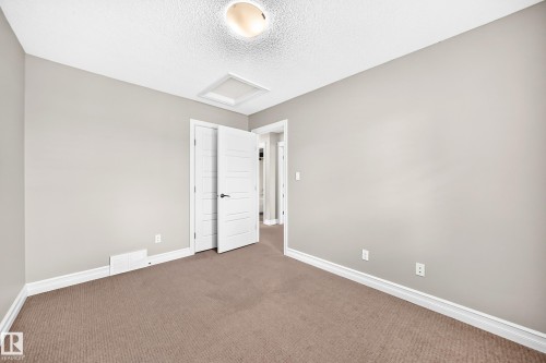Neutral-toned wall paint, white trim, textured ceiling, and brown carpet flooring - 4212 Charles Close Sw, Edmonton, AB - Indoor Photo Showing Other Room
