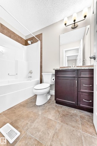 Tub and shower combination with tile surround, a single vanity with stone-finish countertop, and tile flooring - 4212 Charles Close Sw, Edmonton, AB - Indoor Photo Showing Bathroom