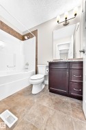 Tub and shower combination with tile surround, a single vanity with stone-finish countertop, and tile flooring - 