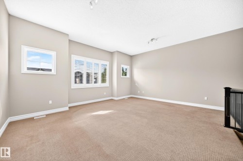 Warm neutral wall tones, textured carpeting, white window casings, and white window shutters - 4212 Charles Close Sw, Edmonton, AB - Indoor Photo Showing Other Room