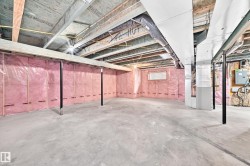 Unfinished basement featuring exposed wood joists, concrete flooring, insulated walls, and a visible electrical panel - 