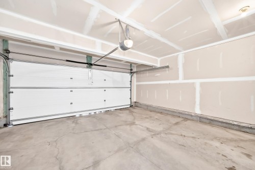 Attached garage with a concrete floor, an overhead garage door, and visible garage door opener mechanism - 4212 Charles Close Sw, Edmonton, AB - Indoor Photo Showing Garage