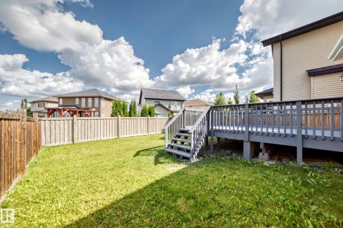Expansive backyard featuring a wood fence, a large deck with stairs, and a vinyl-sided exterior - 4212 Charles Close Sw, Edmonton, AB - Outdoor