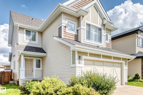Two-story residence featuring light-toned siding, a multi-pane garage door, and a covered entry - 4212 Charles Close Sw, Edmonton, AB - Outdoor