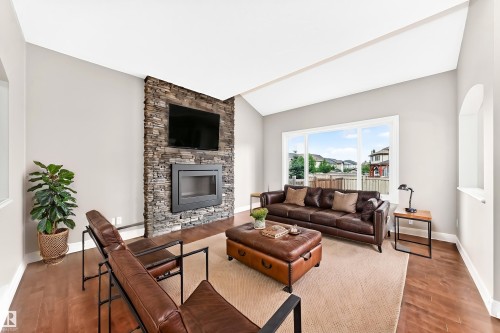 Vaulted ceiling with a stone-clad fireplace and large windows - 4212 Charles Close Sw, Edmonton, AB - Indoor Photo Showing Living Room With Fireplace
