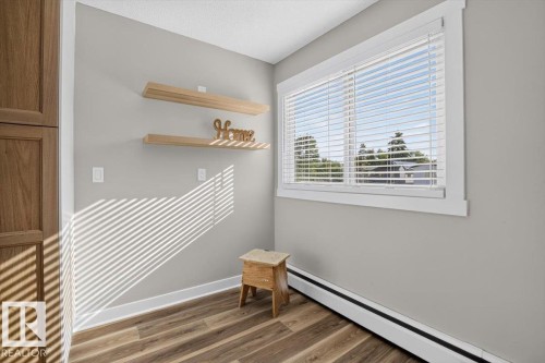 Wood-finish flooring, built-in wooden cabinetry, and two floating wooden shelves - #205 11429 124 St Nw, Edmonton, AB - Indoor Photo Showing Other Room
