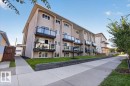 Multi-story building featuring stucco exterior, individual balconies with glass railings, landscaped front yard with retaining wall, and concrete sidewalks - #205 11429 124 St Nw, Edmonton, AB  - Outdoor With Facade 