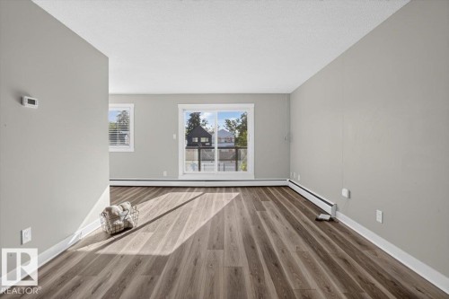 Wood-finish flooring, light gray wall paint, and white trim throughout - #205 11429 124 St Nw, Edmonton, AB - Indoor
