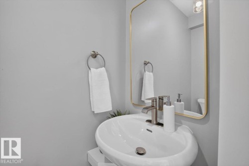 Wall-mounted vanity with a vessel sink, brushed nickel faucet, and a gold-framed mirror - #205 11429 124 St Nw, Edmonton, AB - Indoor Photo Showing Bathroom