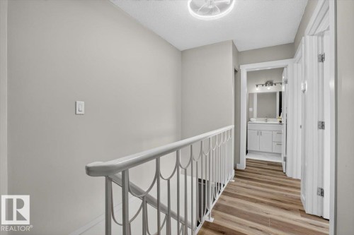 Wood-finish flooring, white railing, and flush-mount ceiling light - #205 11429 124 St Nw, Edmonton, AB - Indoor Photo Showing Other Room