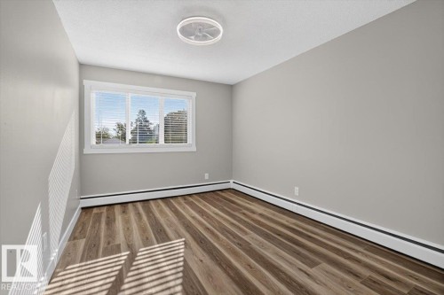 Wood-finish flooring with baseboard heating - #205 11429 124 St Nw, Edmonton, AB - Indoor Photo Showing Other Room
