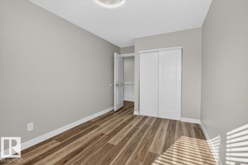 Wood-finish flooring, light gray wall tones, white trim, and a white sliding closet door - #205 11429 124 St Nw, Edmonton, AB - Indoor Photo Showing Other Room