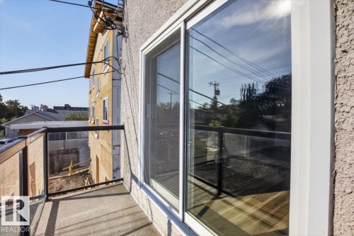 Balcony with glass panel railing and concrete flooring, featuring a large sliding glass door - #205 11429 124 St Nw, Edmonton, AB - Outdoor With Exterior