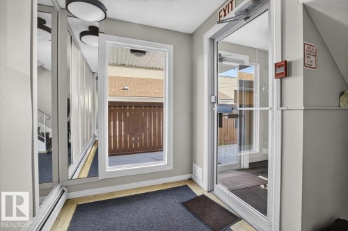 Entryway featuring a full-light glass door, a large fixed window, and mirrored wall panels - #205 11429 124 St Nw, Edmonton, AB - Indoor Photo Showing Other Room