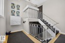 Multilevel staircase with white decorative railing, carpeted treads, and wood-finish flooring - #205 11429 124 St Nw, Edmonton, AB  - Indoor Photo Showing Other Room 