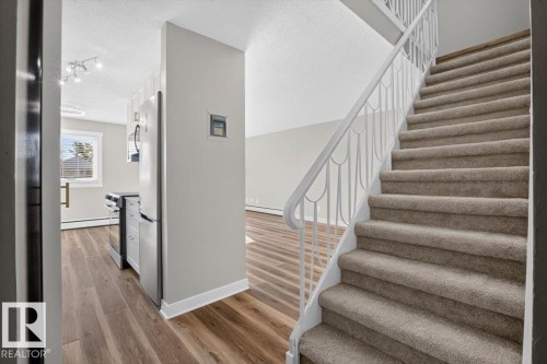 Staircase with carpeted treads and a white metal railing - #205 11429 124 St Nw, Edmonton, AB - Indoor Photo Showing Other Room