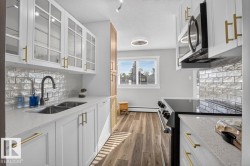 White cabinetry with gold-tone hardware, wood-finish flooring, and a subway tile backsplash - 