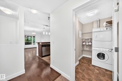 Dedicated laundry area with a stacked washer and dryer, adjacent to wood-finish flooring - 