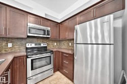 Kitchen featuring rich wood-finish cabinetry, stainless steel appliances, a tiled backsplash, and durable countertops - 