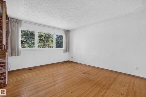 Hardwood flooring throughout, white walls, and a three-lite window. - 16009 93A Avenue Nw, Edmonton, AB - Indoor Photo Showing Other Room