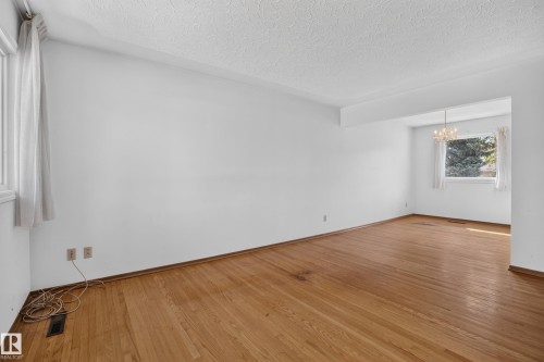 Hardwood flooring, multiple windows, textured ceiling, white walls, and a chandelier - 16009 93A Avenue Nw, Edmonton, AB - Indoor Photo Showing Other Room
