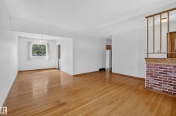 Hardwood flooring throughout, white painted walls, textured ceilings, a brick and wood room divider, and a built-in chandelier - 