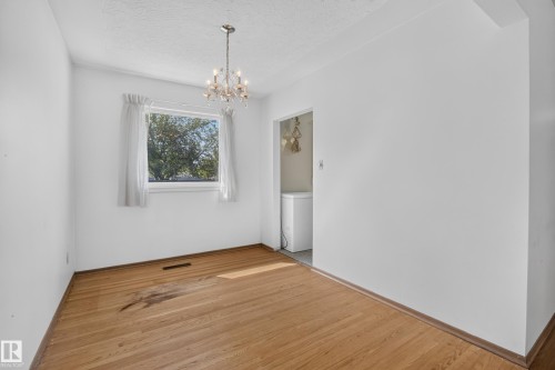 Hardwood flooring paired with a classic chandelier - 16009 93A Avenue Nw, Edmonton, AB - Indoor Photo Showing Other Room