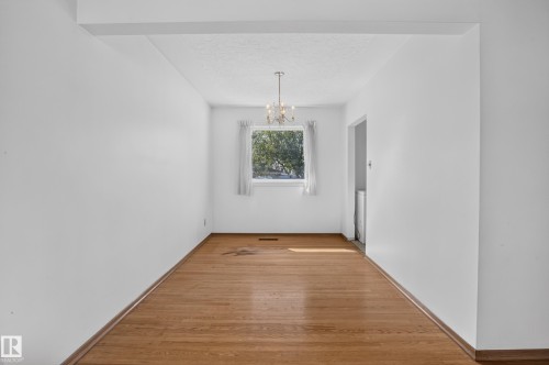 Wood-finish flooring with white walls and a window with a chandelier - 16009 93A Avenue Nw, Edmonton, AB - Indoor Photo Showing Other Room