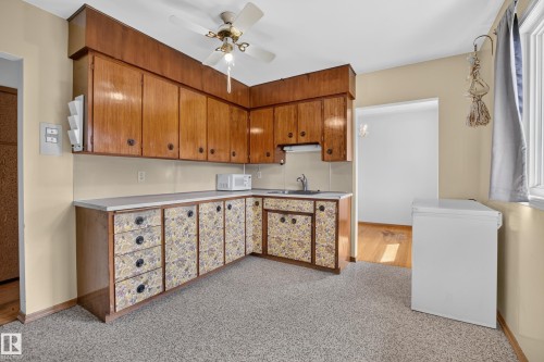U-shaped kitchen with wood-finish upper cabinetry, patterned lower cabinetry, and light-toned countertops - 16009 93A Avenue Nw, Edmonton, AB - Indoor Photo Showing Kitchen