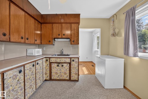 U-shaped kitchen with wood cabinetry, a built-in sink, and a light-colored countertop - 16009 93A Avenue Nw, Edmonton, AB - Indoor