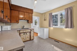 Wood cabinetry, laminate countertops, stainless steel sink, large window, and light-toned flooring - 