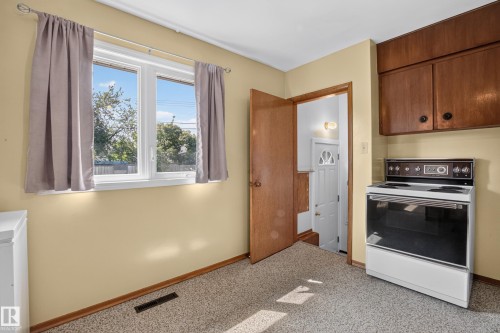 White-framed window, wall-mounted cabinetry, built-in range, and carpet flooring - 16009 93A Avenue Nw, Edmonton, AB - Indoor