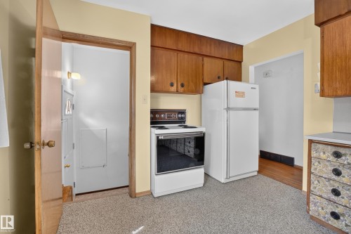 Kitchen featuring wood cabinetry, white appliances, and speckled flooring - 16009 93A Avenue Nw, Edmonton, AB - Indoor Photo Showing Kitchen