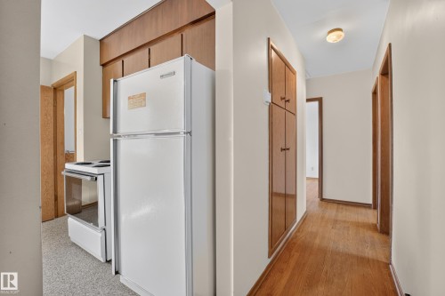 Wood-finish flooring throughout the hallway, built-in cabinetry, and a ceiling-mounted light fixture - 16009 93A Avenue Nw, Edmonton, AB - Indoor