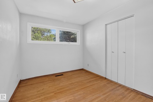 Hardwood flooring with bi-fold closet doors and a rectangular window - 16009 93A Avenue Nw, Edmonton, AB - Indoor Photo Showing Other Room