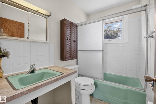 Wall-mounted vanity with a green rectangular sink, chrome faucet, and mirrored medicine cabinet - 16009 93A Avenue Nw, Edmonton, AB - Indoor Photo Showing Bathroom