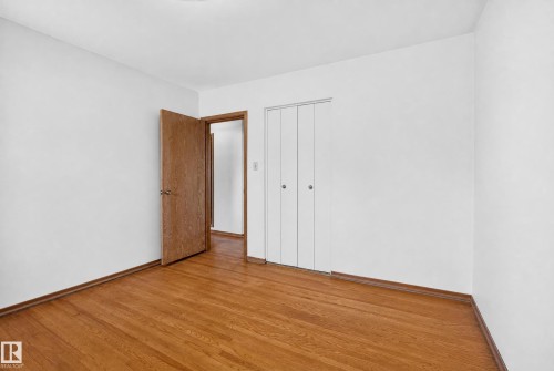 Hardwood flooring, painted white walls, wood-finish interior door, bifold closet doors - 16009 93A Avenue Nw, Edmonton, AB - Indoor Photo Showing Other Room