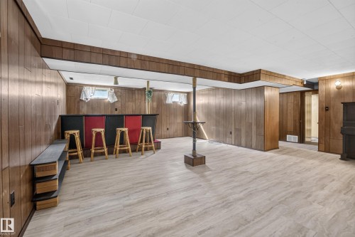 Lower level featuring wood-finish wall paneling, a built-in bar, and light-toned flooring - 16009 93A Avenue Nw, Edmonton, AB - Indoor