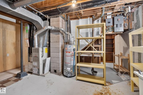 Exposed ceiling joists, concrete block wall construction, forced-air furnace system, water heater, and electrical service panels - 16009 93A Avenue Nw, Edmonton, AB - Indoor Photo Showing Basement
