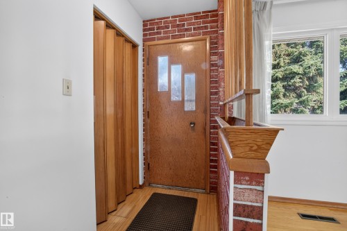 Entryway featuring a wood-finish door with frosted glass inserts, red brick accent wall, and wood-finish flooring - 16009 93A Avenue Nw, Edmonton, AB - Indoor Photo Showing Other Room