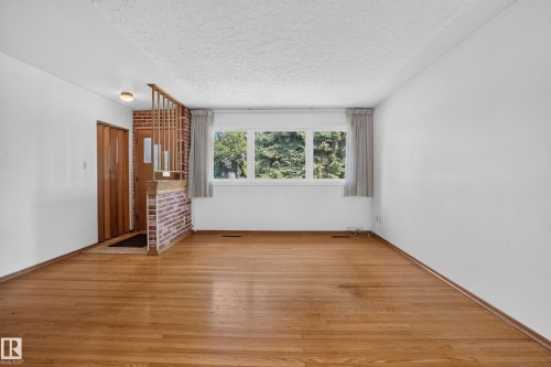 Warm wood-finish flooring with white walls and a three-lite Window - 16009 93A Avenue Nw, Edmonton, AB - Indoor Photo Showing Other Room