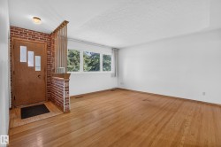 Wood-finish flooring, brick accent wall, wood door with decorative glass inserts, and a three-lite window. - 
