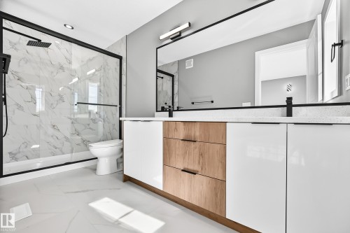 Double vanity with white and wood-finish cabinetry, white countertops, and matte black fixtures - 426 Crystal Creek Link, Leduc, AB - Indoor