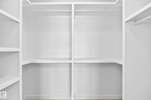 Integrated white shelving system with multiple storage levels and hanging rods - 426 Crystal Creek Link, Leduc, AB - Indoor With Storage