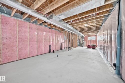 Unfinished lower level with exposed ceiling joists, pink insulation, and concrete flooring - 426 Crystal Creek Link, Leduc, AB - Indoor Photo Showing Basement