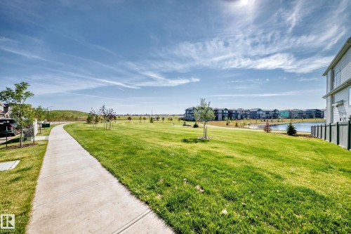 Expansive green space featuring a paved walking path, mature trees, and a tranquil pond - 426 Crystal Creek Link, Leduc, AB - Outdoor With View