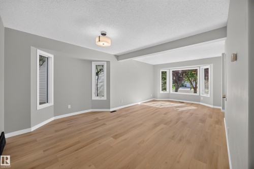Light wood-finish flooring, multiple bay windows, recessed lighting, and a neutral wall palette - 3640 31 Street Nw, Edmonton, AB - Indoor Photo Showing Other Room