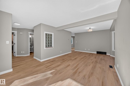 Open-concept living space featuring wood-finish flooring, recessed lighting, and a glass block window - 3640 31 Street Nw, Edmonton, AB - Indoor Photo Showing Other Room