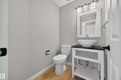 Pedestal vanity with a vessel sink, dark countertop, and rectangular framed mirror - 3640 31 Street Nw, Edmonton, AB - Indoor Photo Showing Bathroom